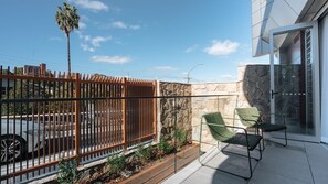 A balcony with a stone wall, a metal fence, and a car parked in the background. - The Elara, Neutral Bay Isyd (Neutral Bay)