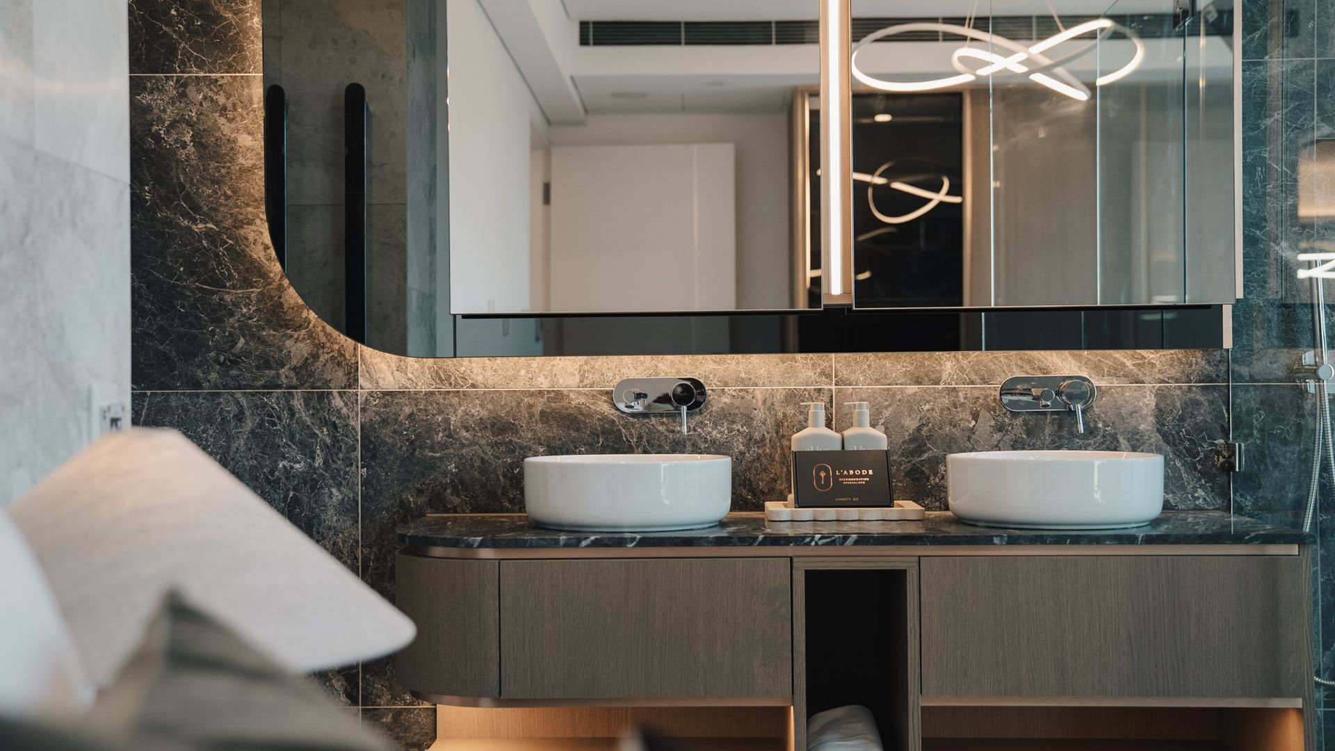 Uma casa de banho moderna com duas lavatórios, um espelho grande e zona de duche.