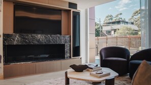 Ein modernes Wohnzimmer mit eingebautem Kamin, einer Sitzecke mit Sofa und Sesseln sowie Blick auf den Balkon.