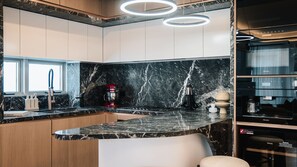 Eine moderne Küche mit Marmor-Spritzschutz, einer integrierten Kochinsel und einem Weinkühlschrank.