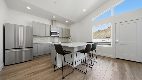 Una cocina moderna con una isla central, electrodomésticos de acero inoxidable y vistas a un paisaje montañoso.