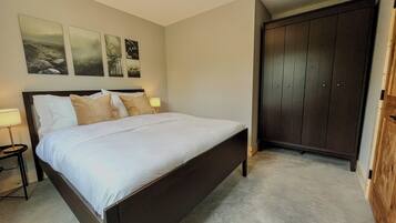 A bedroom with a bed, a nightstand, a lamp, a wardrobe, and wall art.
