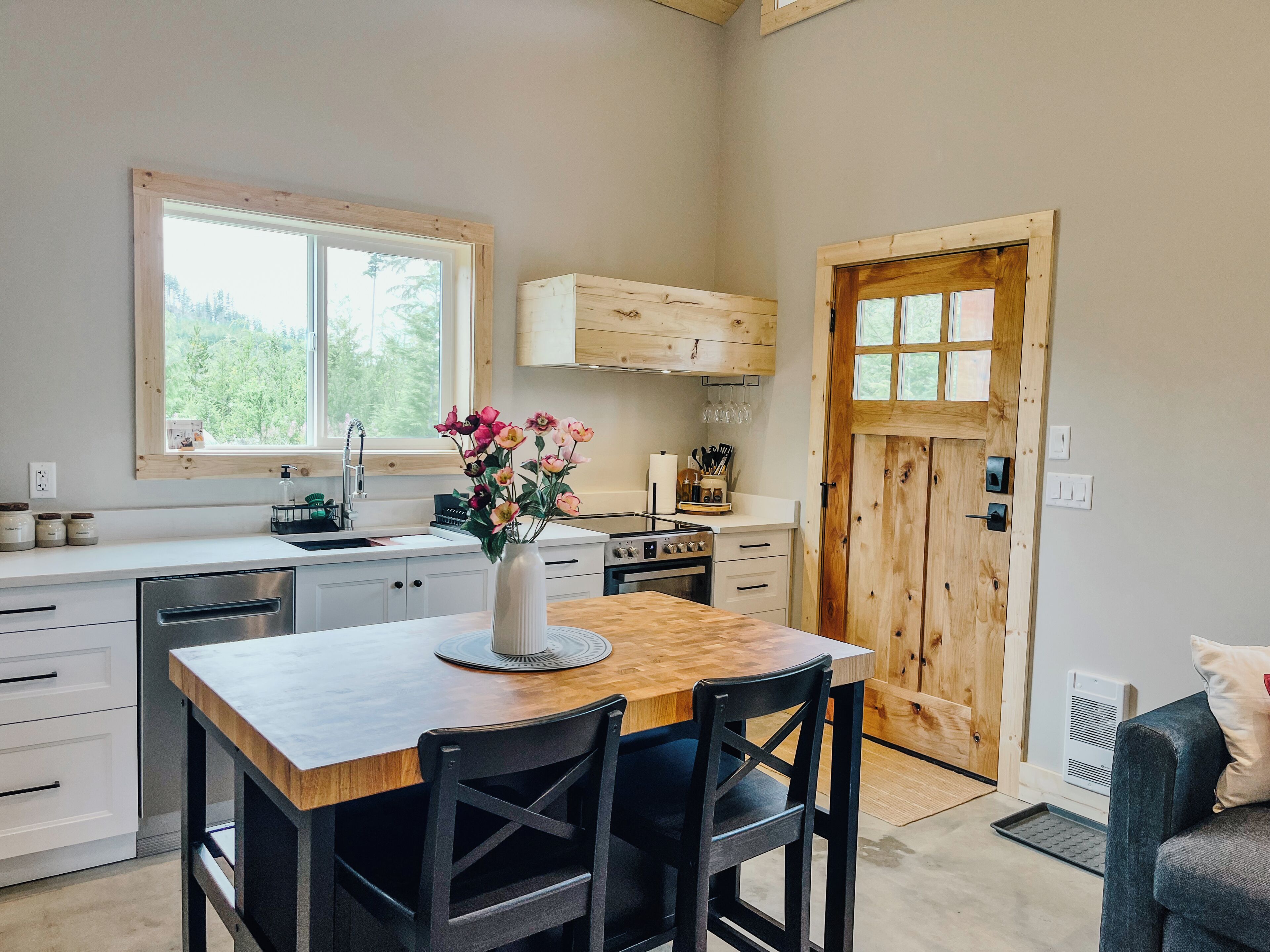 A kitchen with a wooden table, chairs, a stove, and a window.