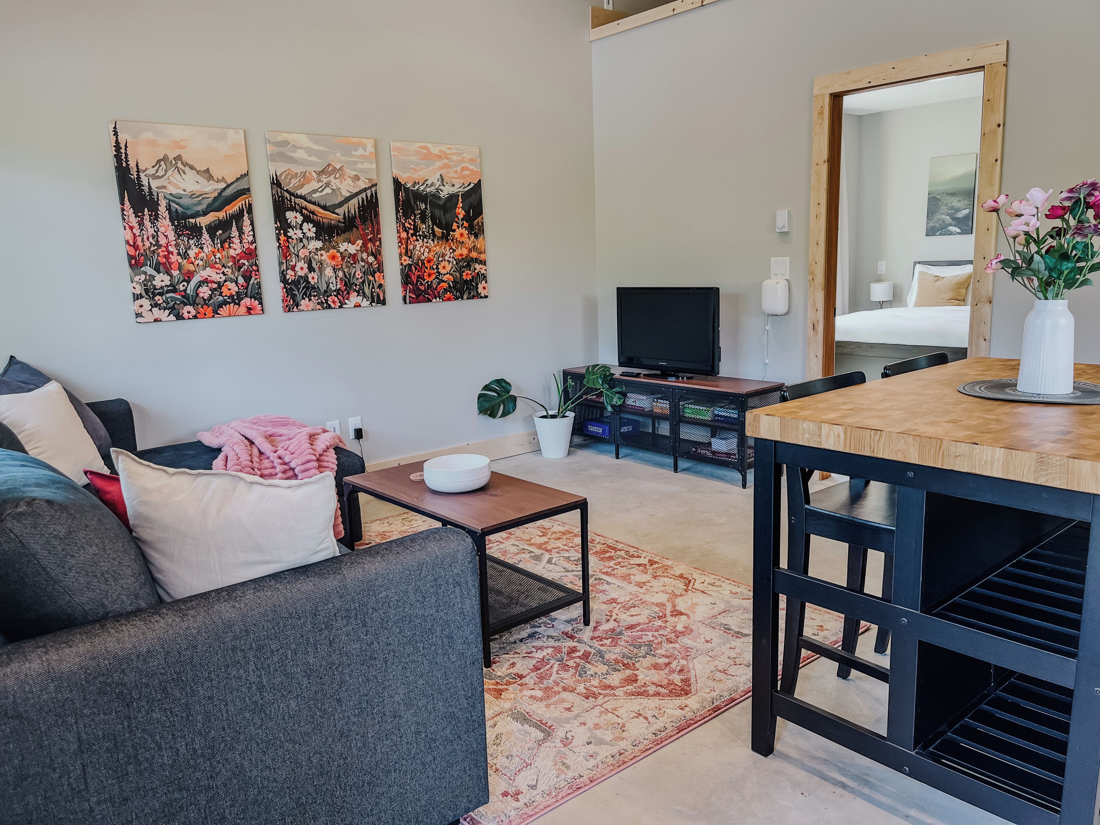 Una sala de estar con sofá, mesa de centro, mueble para televisor y un comedor con mesa y sillas.