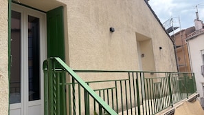 A building with a green metal balcony railing, a door with green shutters, and a textured wall. - Tout à pied:plage, commerces et gare (Banyuls-sur-Mer)