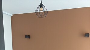 Un dormitorio con una cama, dos mesitas de noche, un aplique de pared y un enchufe.