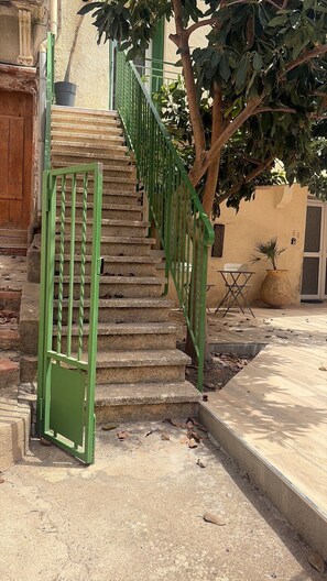 A staircase with green railings leading to a door, a tree, and a small table with chairs. - Tout à pied:plage, commerces et gare (Banyuls-sur-Mer)