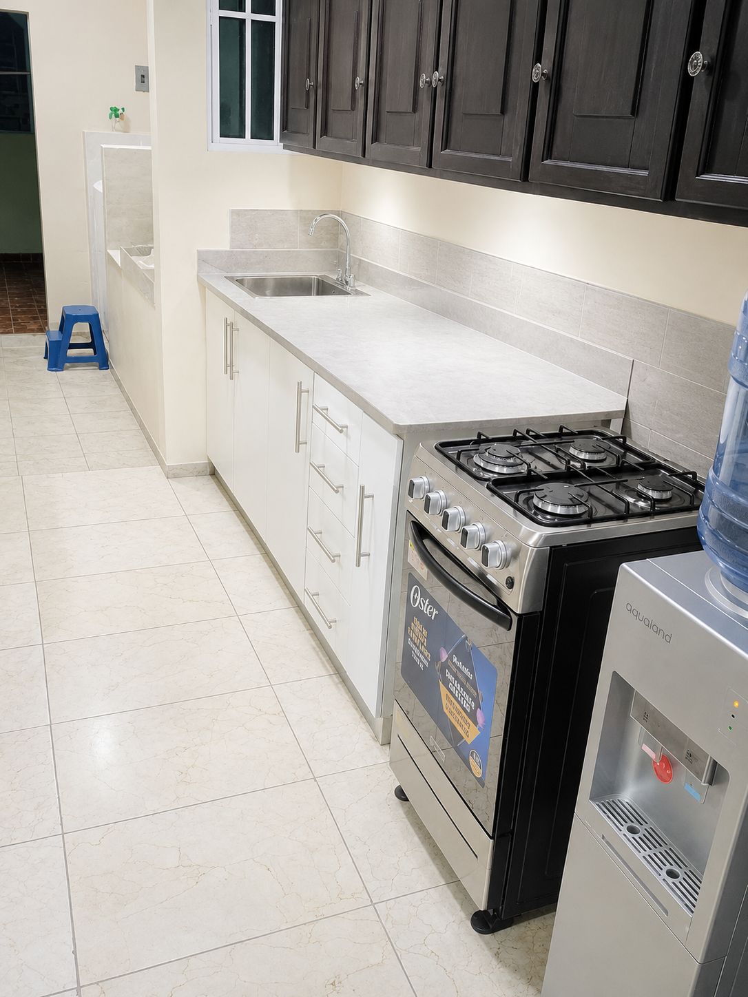 Una cocina con estufa, lavamanos y alacenas.