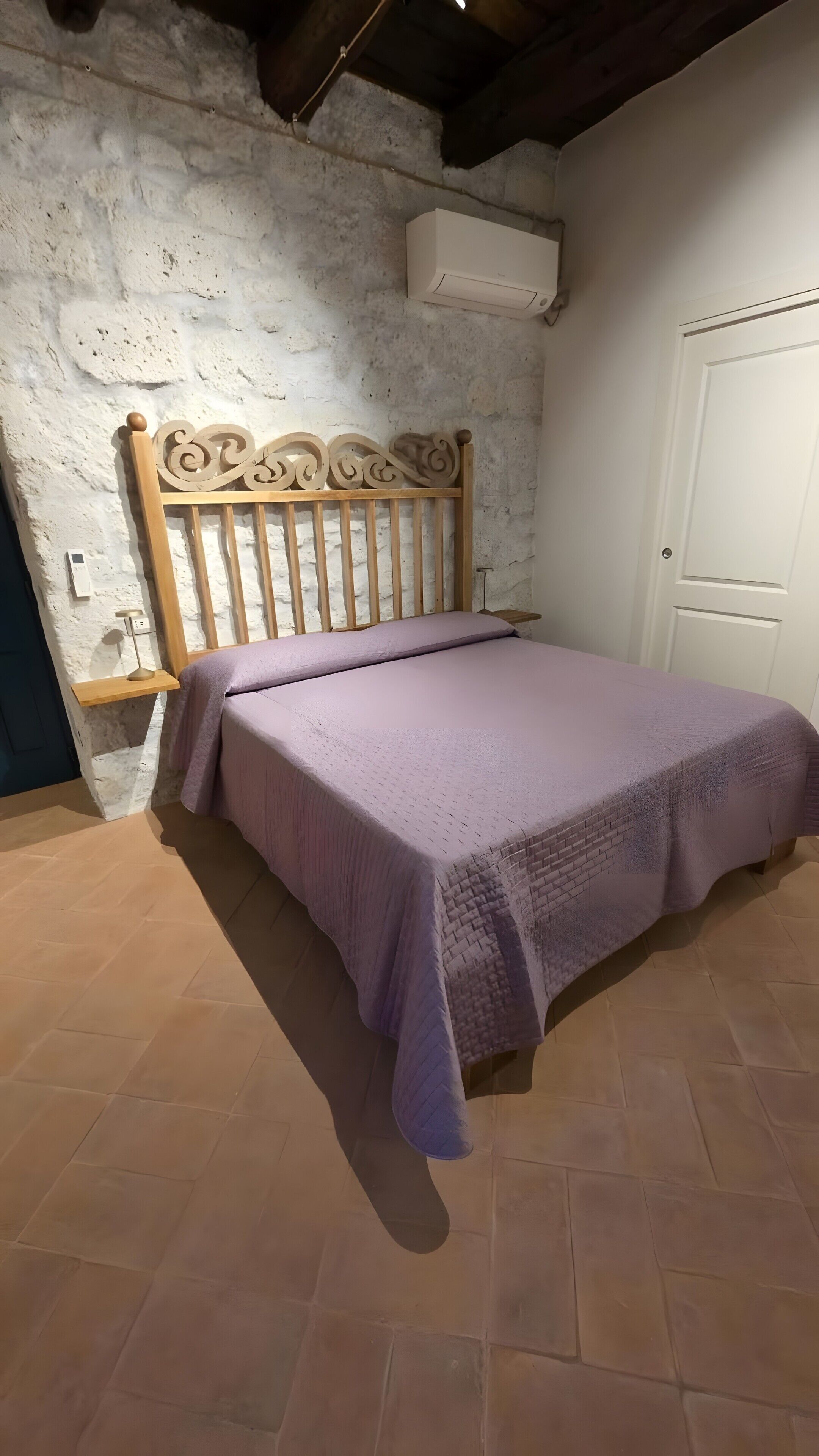Un dormitorio con estructura de cama de madera, pared blanca, puerta blanca y ventilador de techo.
