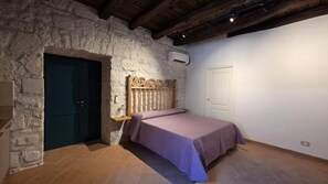 Un dormitorio con pared de piedra, estructura de cama de madera, una puerta y un equipo de aire acondicionado.