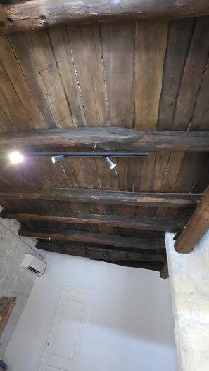 Una habitación con techo de madera inclinado, una puerta blanca y una pared blanca.