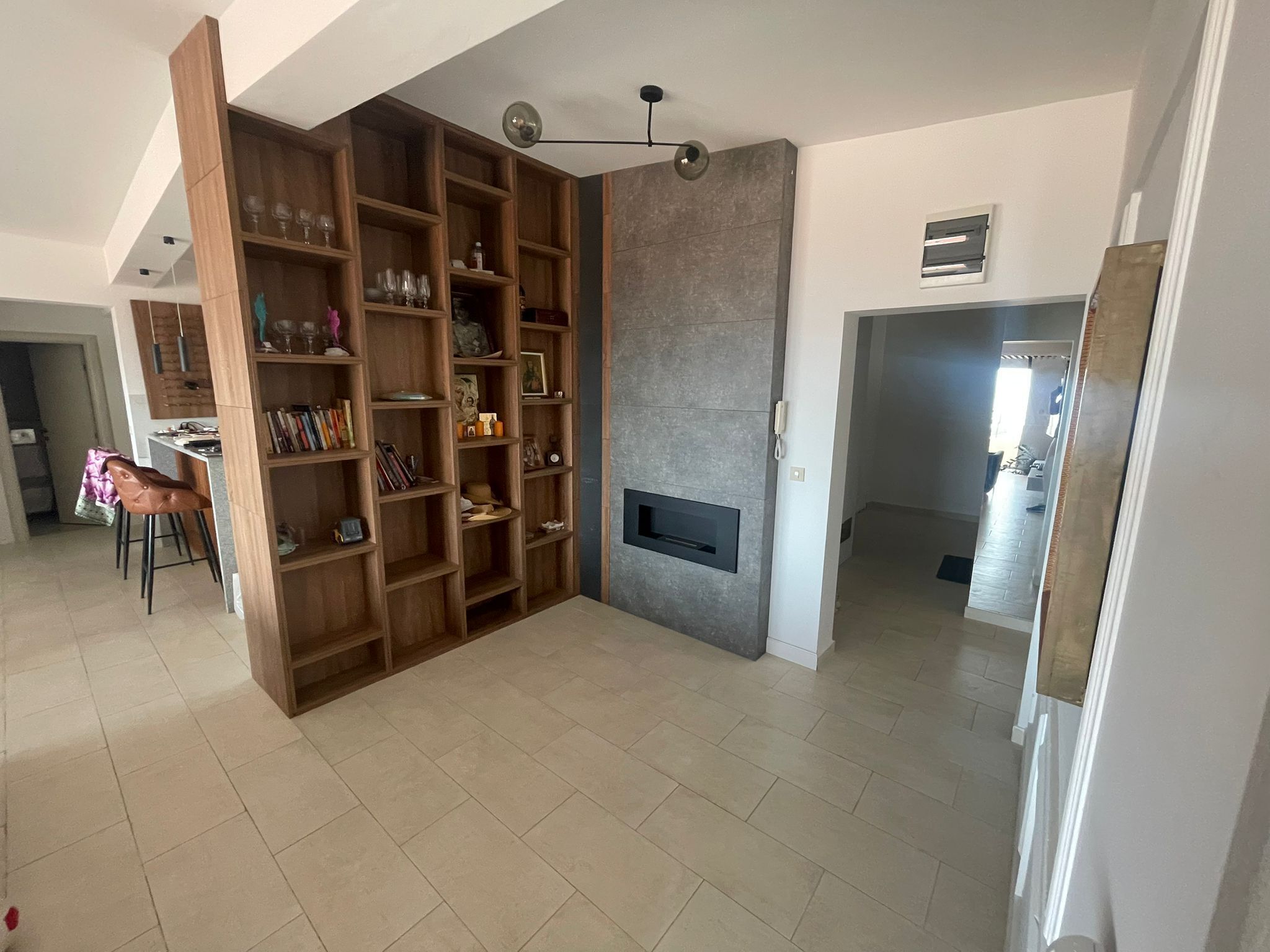 Un amplio salón con una estantería empotrada de madera, una chimenea hundida y un comedor con una silla y mesa.