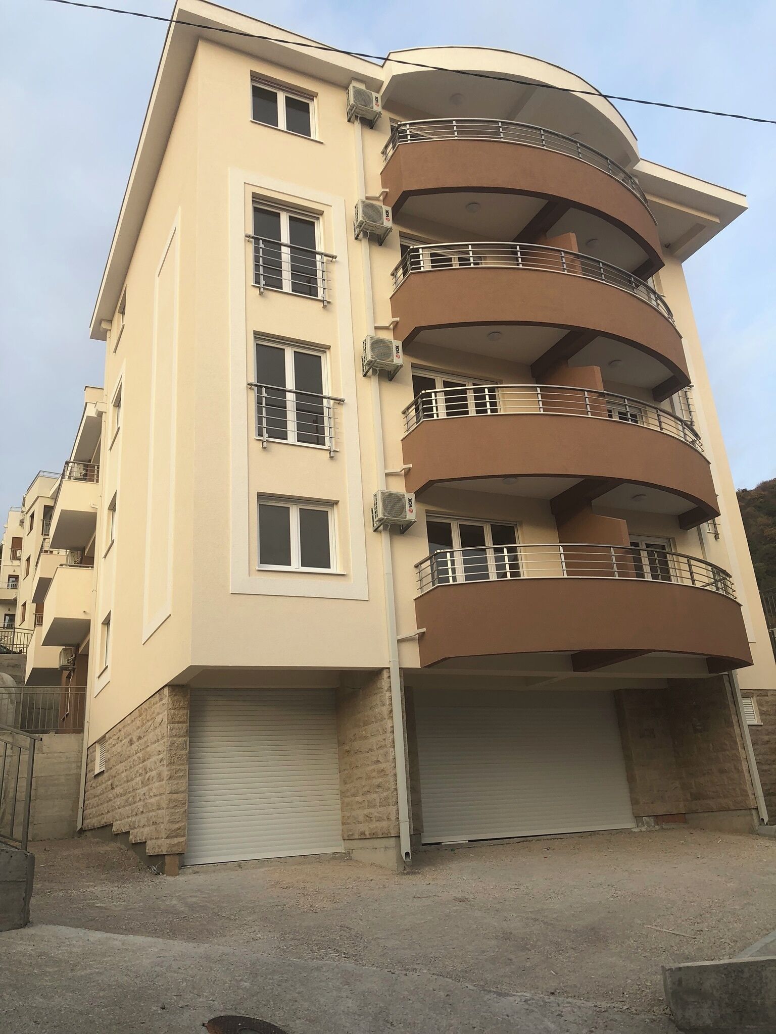 A multi-story residential building with balconies, air conditioning units, and a garage.