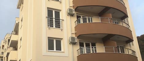 A multi-story residential building with balconies, air conditioning units, and a garage.