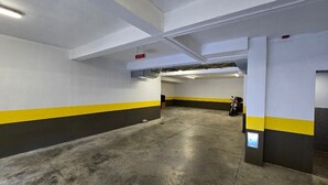 Sisätiloissa sijaitseva pysäköintihalli, jossa on betonilattiat ja valkoiseksi, keltaiseksi ja mustaksi maalatut seinät.