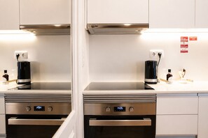 A kitchen with two ovens, a coffee maker, and a digital clock. - D&S - Mercado dos Poetas Porto (Porto)