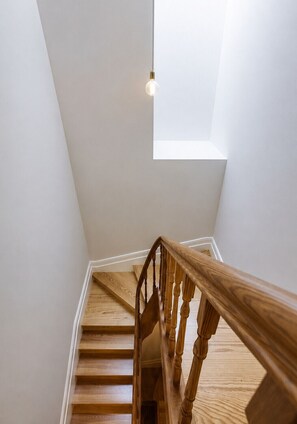 A wooden staircase with a white wall and a skylight above. - D&S - Mercado dos Poetas Porto (Porto)