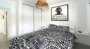 Ein modernes Schlafzimmer mit einem Bettzeug mit ZEBRA-MUSTER, einem gerahmten Kunstwerk über dem Bett und einer Hängeleuchte.