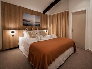 A modern hotel room with a wooden headboard, a large bed with a brown bedspread, and a painting above the bed. - Residence Océan&Foret: T2 appartement, 1 chambre avec terrasse (Anglet)