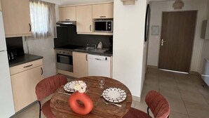 Eine moderne Küche mit Esstisch für zwei Personen, einer Mikrowelle, einem Backofen und einem Geschirrspüler.