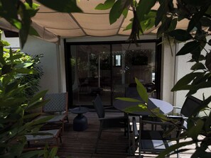 An outdoor patio with a covered seating area, a table, and chairs. - Residence Océan & Forêt : T2 appartement 1 chambre, en RDJ avec terrasse (Anglet)