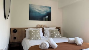 Une chambre d’hôtel avec un lit, des oreillers, un tableau, une table de chevet et des serviettes.