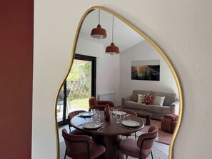 A dining area with a round table set for six, surrounded by six chairs. - T2 appartement 1 chambre, en RDJ avec terrasse (Anglet)