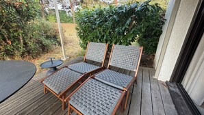 A wooden deck with two wicker chairs and a small round table. - T3 appartement 2 chambres RDJ avec terrasse (Anglet)