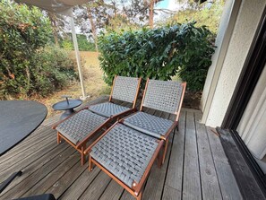 A wooden deck with two wicker chairs and a small round table. - T3 appartement 2 chambres RDJ avec terrasse (Anglet)
