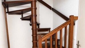 A wooden spiral staircase with a handrail and a door at the bottom. - T3 appartement 2 chambres RDJ avec terrasse (Anglet)