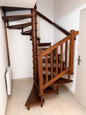 A wooden spiral staircase with a handrail and a door at the bottom. - T3 appartement 2 chambres RDJ avec terrasse (Anglet)