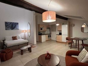 Ein kompakter Wohnraum mit Sofa, Esstisch, Küchenzeile und kleinem Esstisch.
