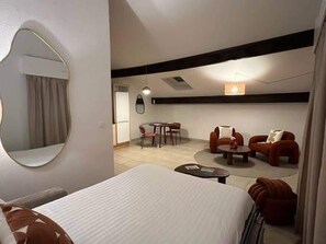 Een hotelkamer met een bed, een ronde spiegel, een zithoek met stoelen en een bank.