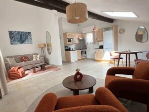 Ein modernes Wohnzimmer mit einer Couch, Sesseln, einem Couchtisch und einem Essbereich mit Tisch und Stühlen.