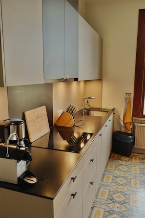 Een moderne keuken met een roestvrijstalen aanrecht, een koffiezetapparaat, een snijplank en een spoelbak.