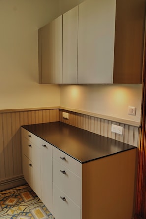 Een keuken met witte kastjes, een zwart aanrecht en een vloer met een patroon.