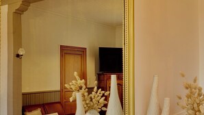 Una habitación con un espejo grande, piso de madera y sofá rojo.