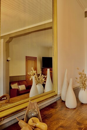 A room with a large mirror, a wooden floor, and a red sofa. - A Trip to the Canal (Moissac)