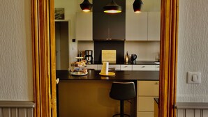 Una cocina moderna con una isla central, iluminación colgante y vistas al área de comedor a través de un acceso.