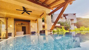 A clear view of an infinity pool with a ceiling fan, a door leading to a room, and a view of the surrounding buildings. - Vista Coral • Beachfront Condo • Jacuzzi & Pool • Ixtapa-Zihuatanejo (Ixtapa Zihuatanejo)