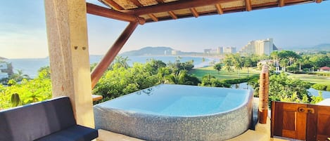 A hot tub with a view of the ocean and cityscape.