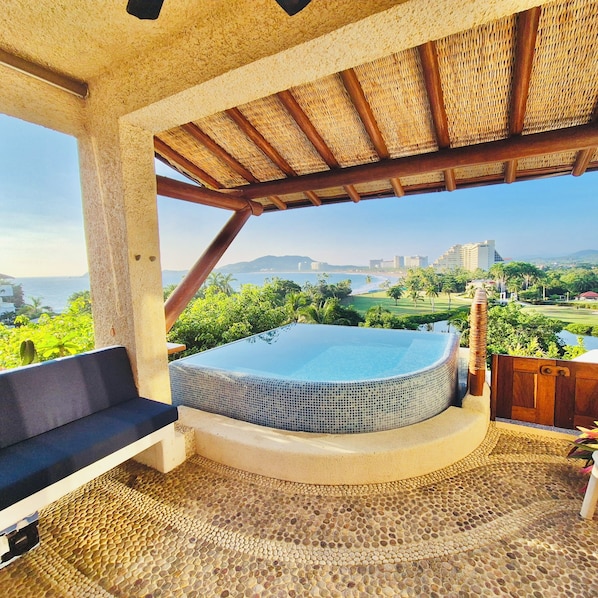 A hot tub with a view of the ocean and cityscape.