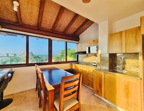 A kitchen with wooden cabinets, a granite countertop, and a view of the city.