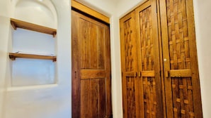 A hallway with a white wall, a wooden door with a simple design, and a wooden door with a lattice pattern. - Vista Coral • Beachfront Condo • Jacuzzi & Pool • Ixtapa-Zihuatanejo (Ixtapa Zihuatanejo)