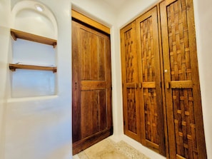 A hallway with a white wall, a wooden door with a simple design, and a wooden door with a lattice pattern.