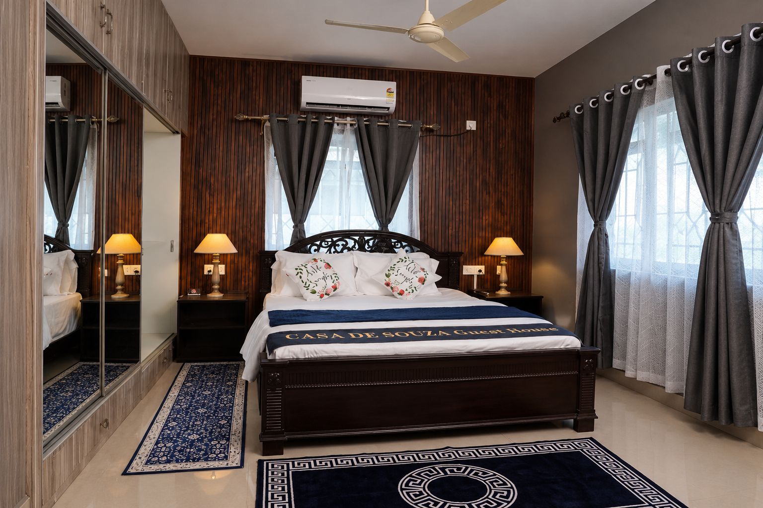 A hotel room with a bed, bedside lamps, a ceiling fan, and a window with curtains.