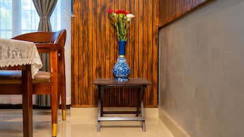 A wooden chair with a lace tablecloth, a small wooden table with a vase of flowers, and a wooden wall with vertical planks.