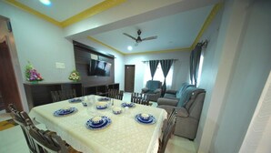 A dining area with a table set for four, a television, and a ceiling fan. - Casa de Souza (Verna)
