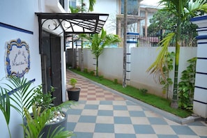 A hotel corridor with a checkered floor, a covered entrance, and potted plants.