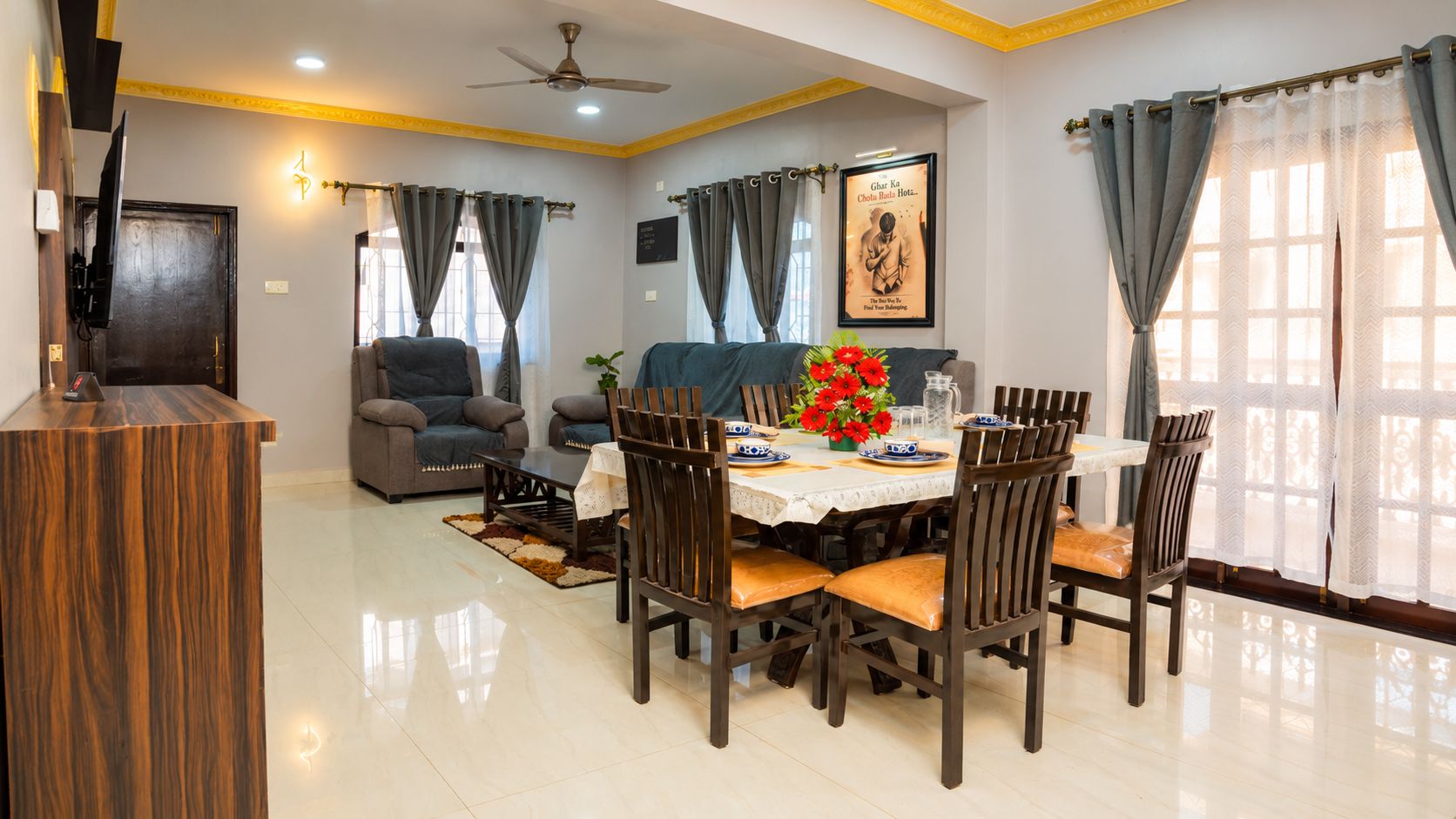 A dining area with a round table, chairs, and a ceiling fan.